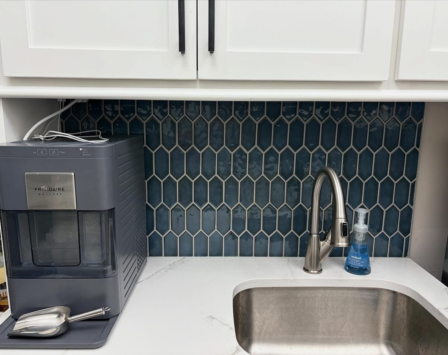 Navy blue elongated hex tile backsplash behind a kitchen sink